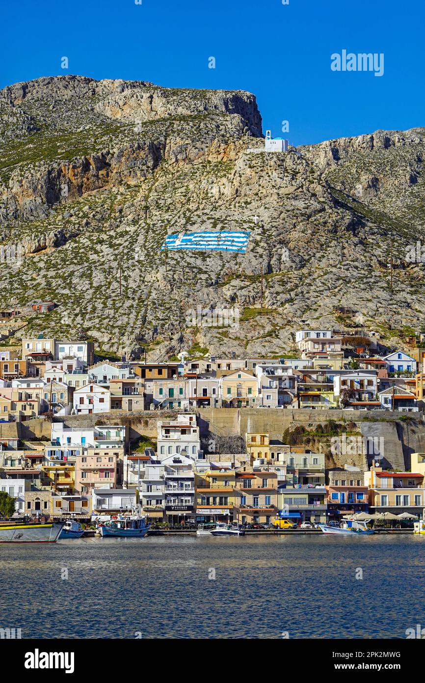 Cappella bianca e bandiera greca dipinta sulla collina sopra Pothia, la città principale di Kalymnos, isola greca, Isole Dodecanesi, Grecia Foto Stock