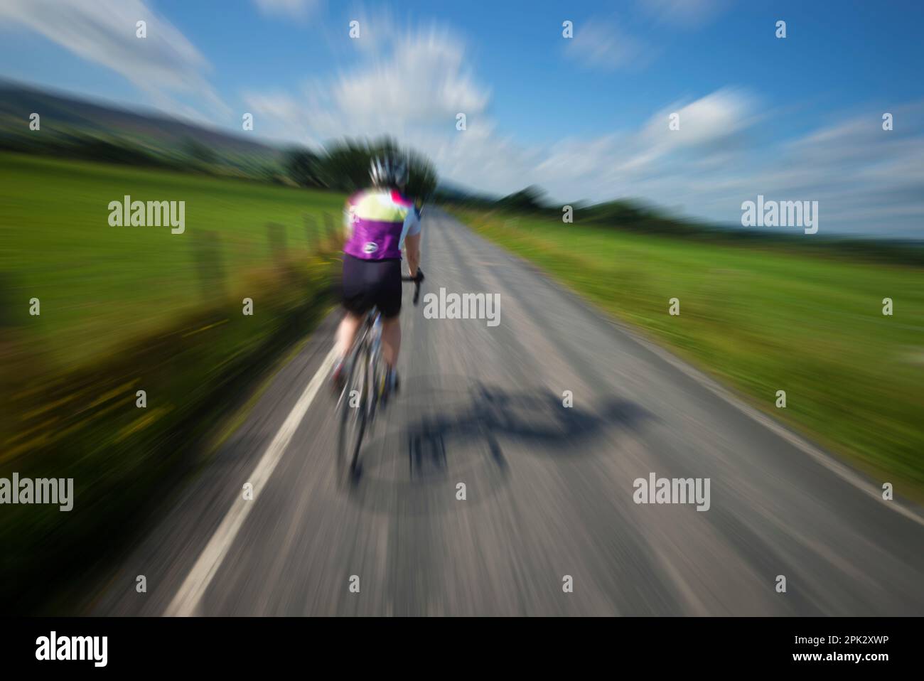 Ciclista stradale femminile che zoomata lungo le corsie di Bowland, Lancashire, Regno Unito. Foto Stock