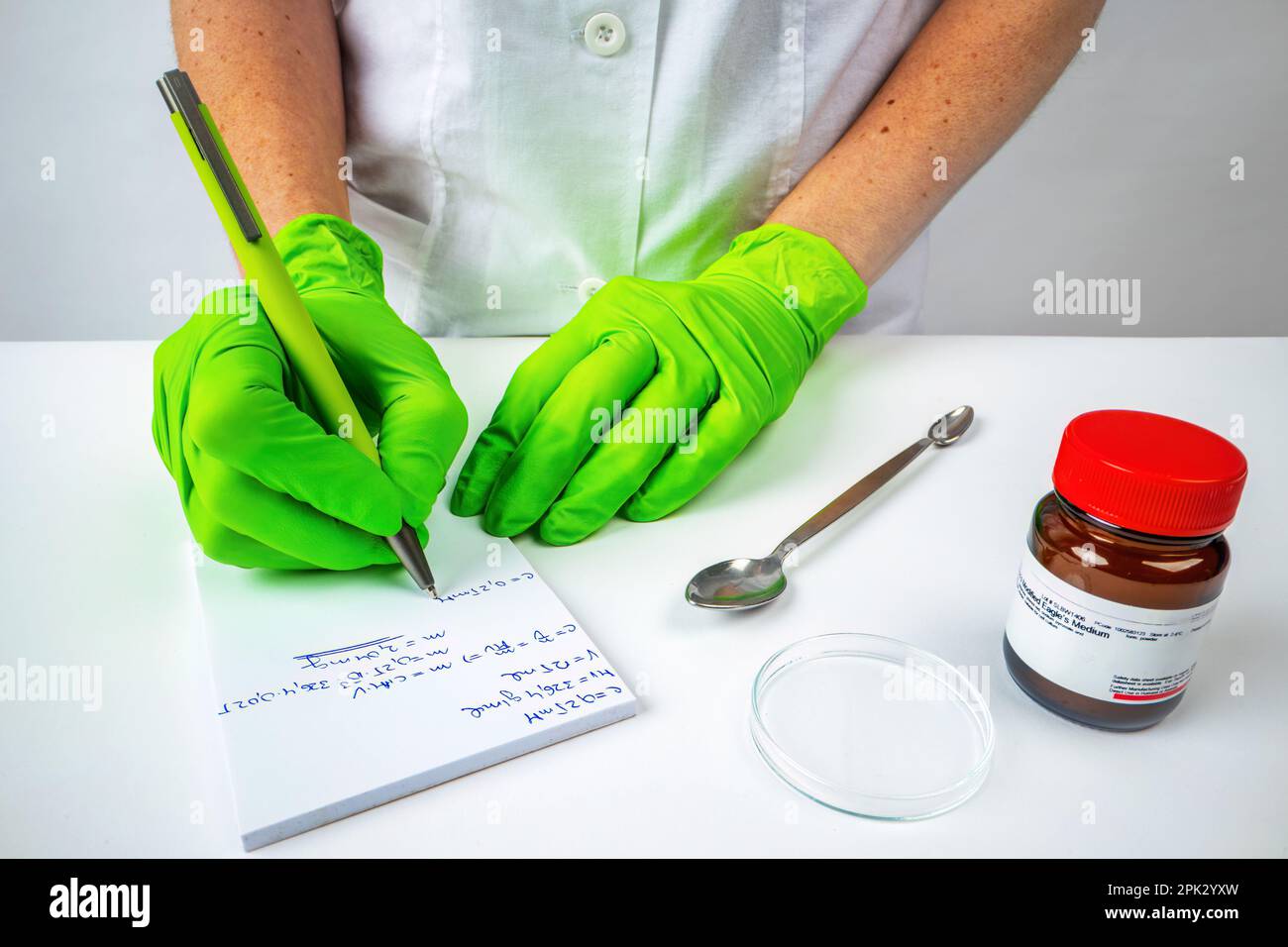 Il medico scienziato scrive delle note durante la sua ricerca in un quaderno accanto alla fiala con dei campioni Foto Stock