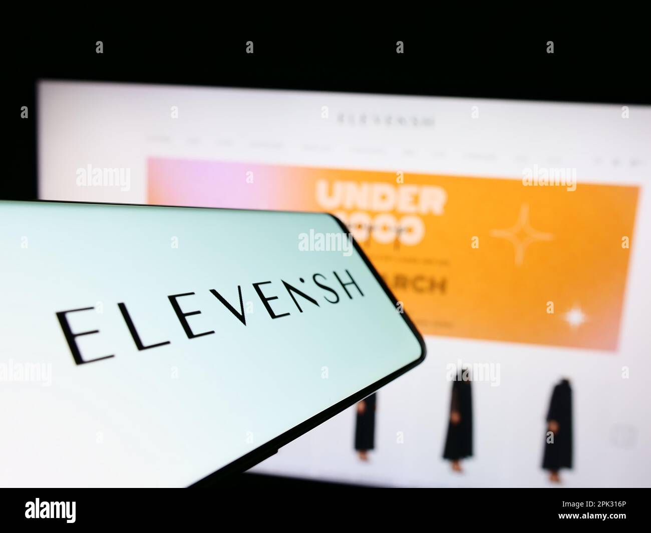 Telefono cellulare con logo della società ELEVENISH Emirati e-commerce sullo schermo di fronte al sito web aziendale. Messa a fuoco al centro a destra del display del telefono. Foto Stock