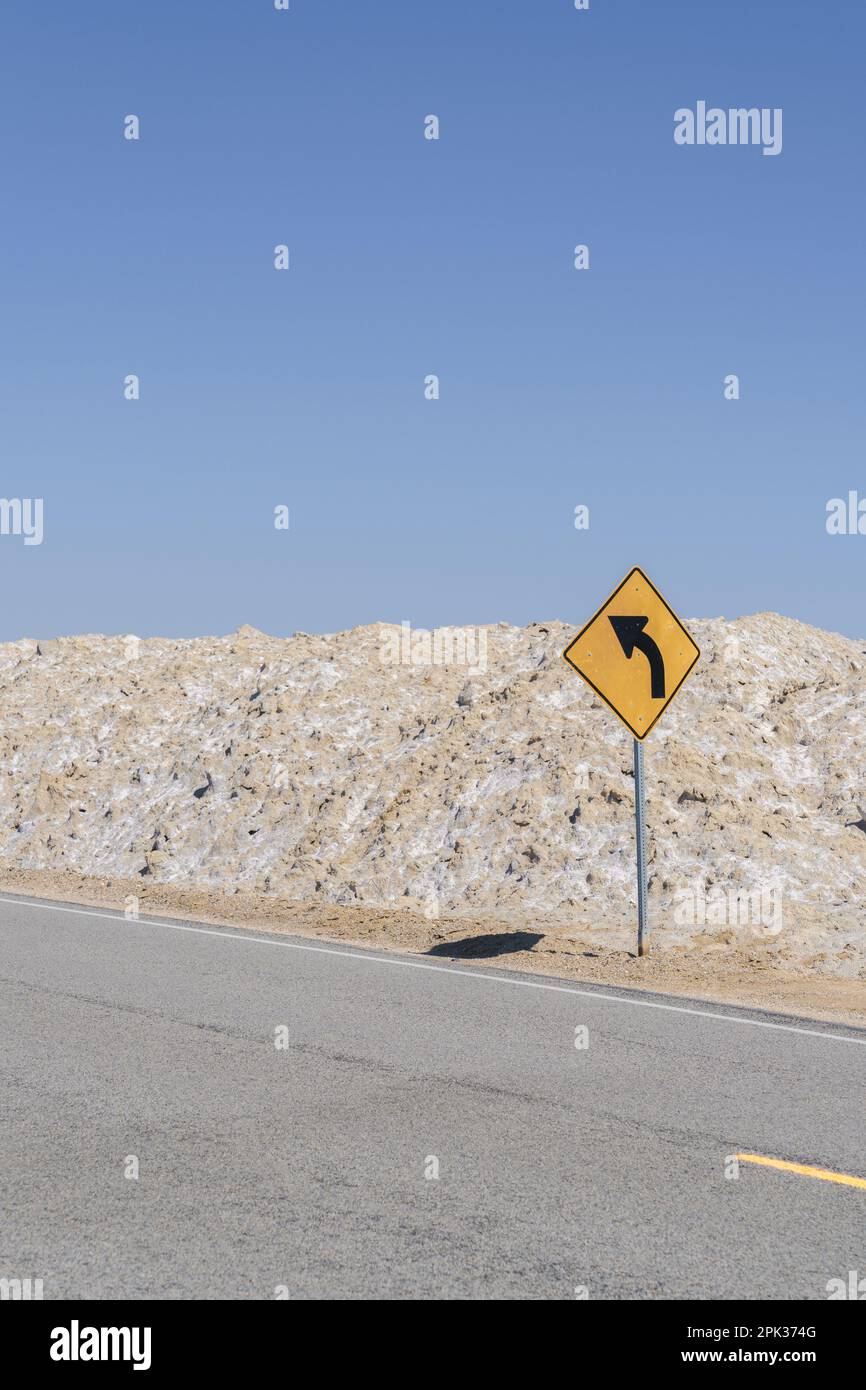 Curva davanti segno di attenzione su una strada solitaria desolata nel deserto di Mojave di Amboy, California Foto Stock