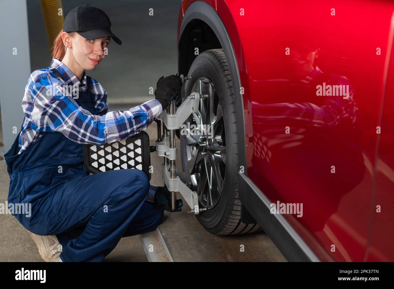 Un meccanico auto femminile fa una campanatura. Donna che lavora in un servizio auto. Foto Stock