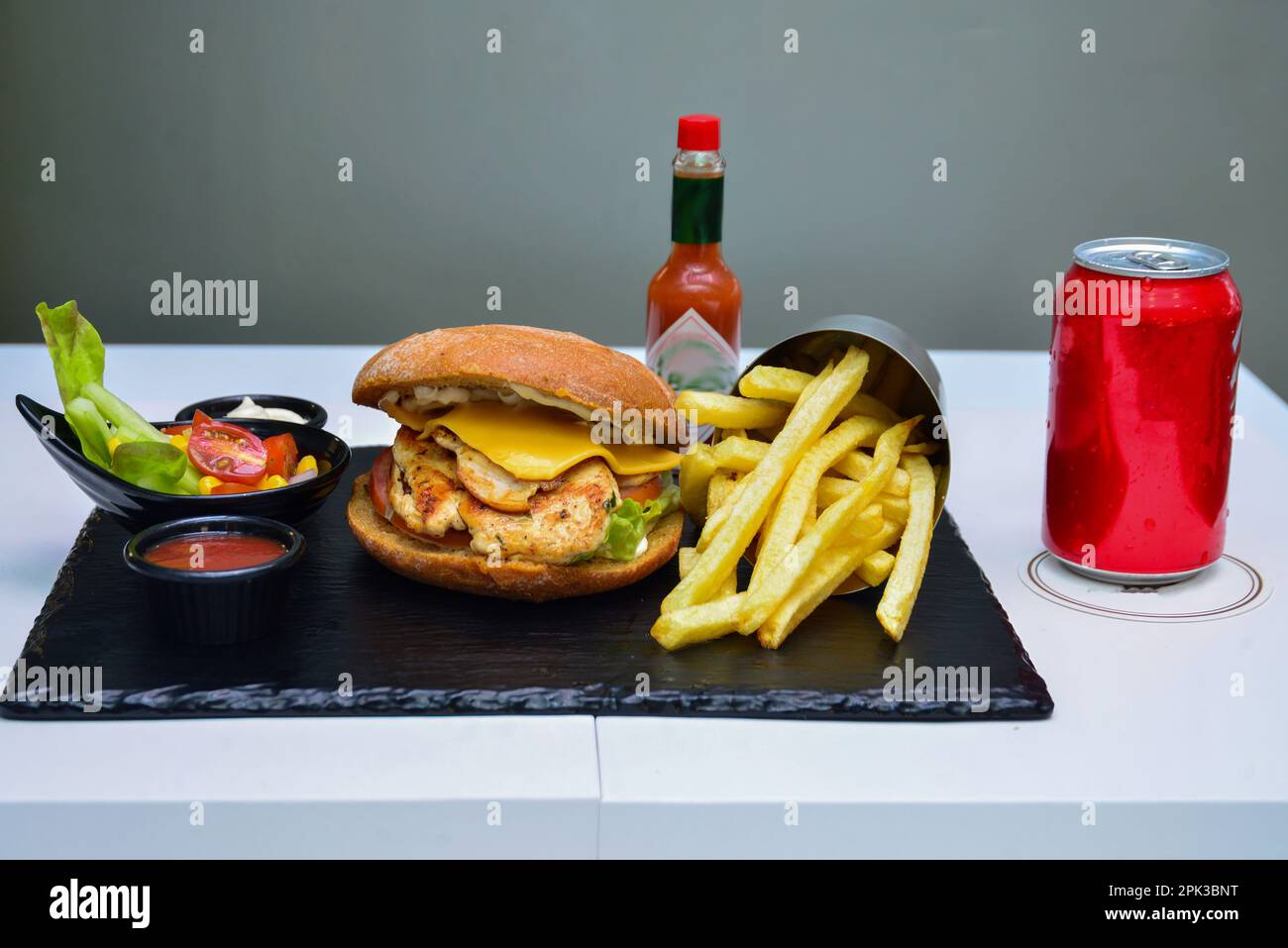 Hamburger di pollo e formaggio. Con insalata e bevanda analcolica su marmo nero Foto Stock