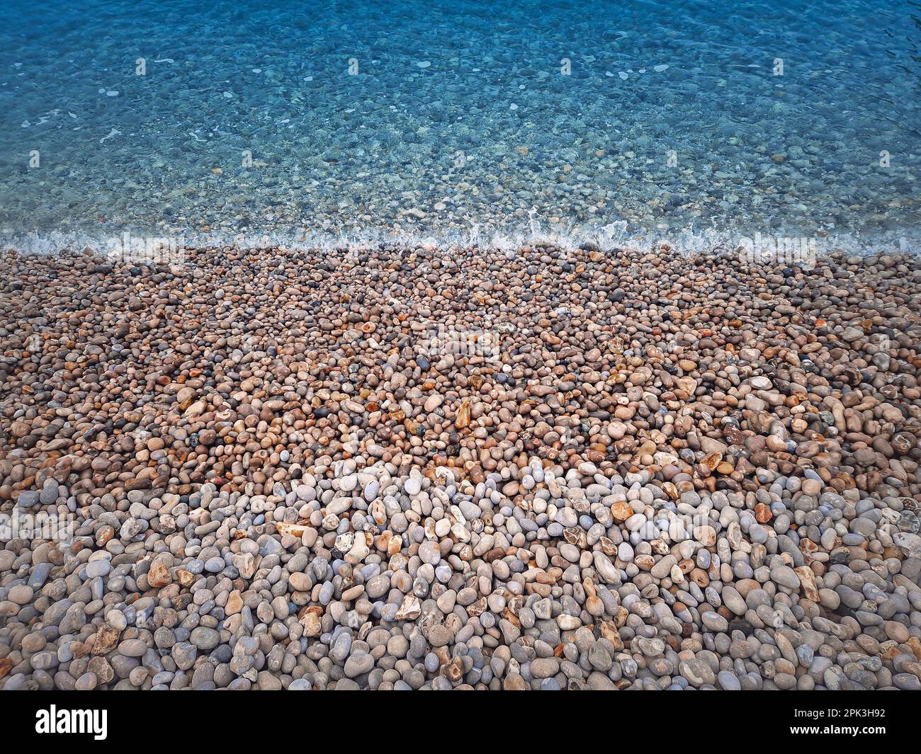Rocce di ghiaia spiaggia e blu acqua di mare struttura Foto Stock