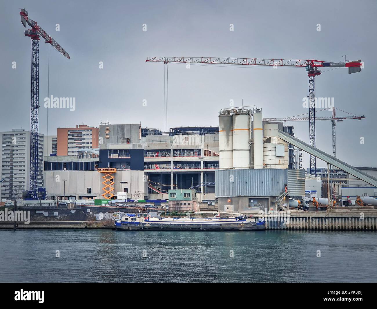 Sito di costruzione affollato vicino alla Senna con gru funzionanti e una chiatta sull'acqua, Asnieres, Parigi, Francia Foto Stock
