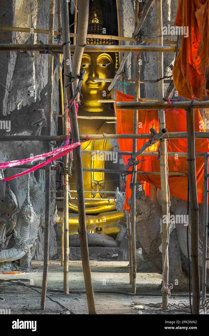 Statua di Buddha e un vestito arancione in una grotta di bambù ancora in posizione, ancora incompiuta e realizzata con impalcature di bambù. Foto Stock