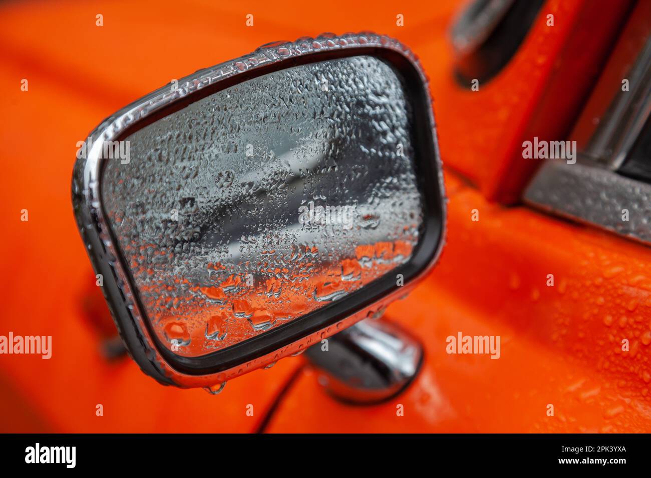 Specchietto retrovisore di un'auto retrò arancione nel closeup pioggia Foto Stock