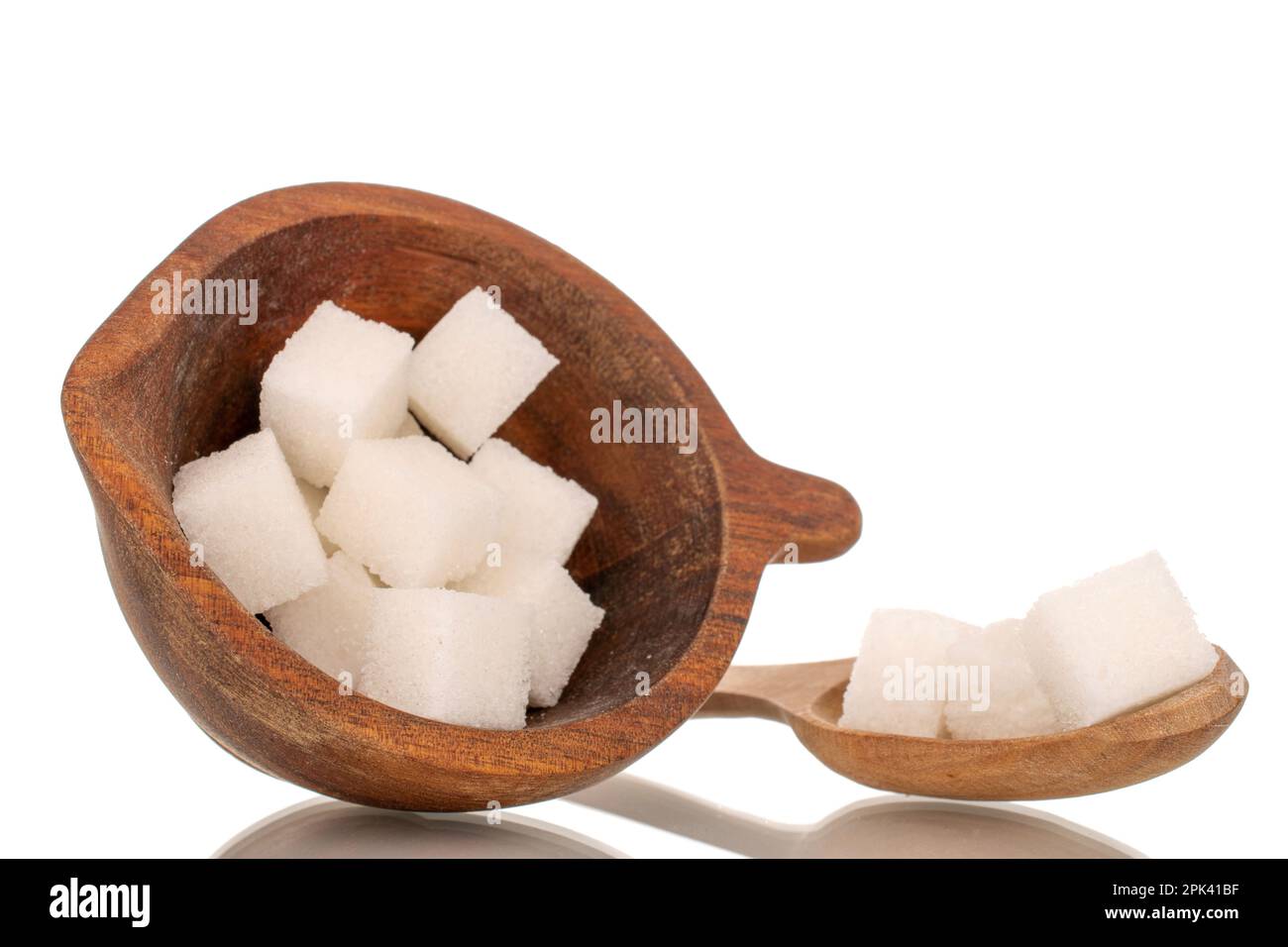 Diversi cubetti di zucchero bianco con coppa di legno e cucchiaio, macro, isolato su fondo bianco. Foto Stock