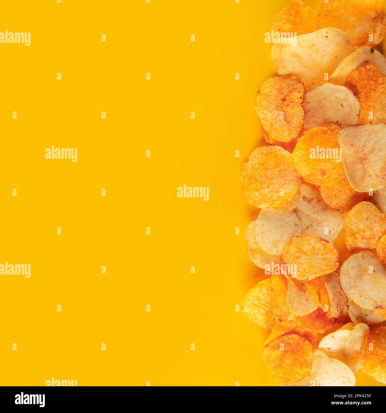 Bordo di patatine isolato su sfondo arancione brillante. Nibble deliziosamente coinvolgente Foto Stock