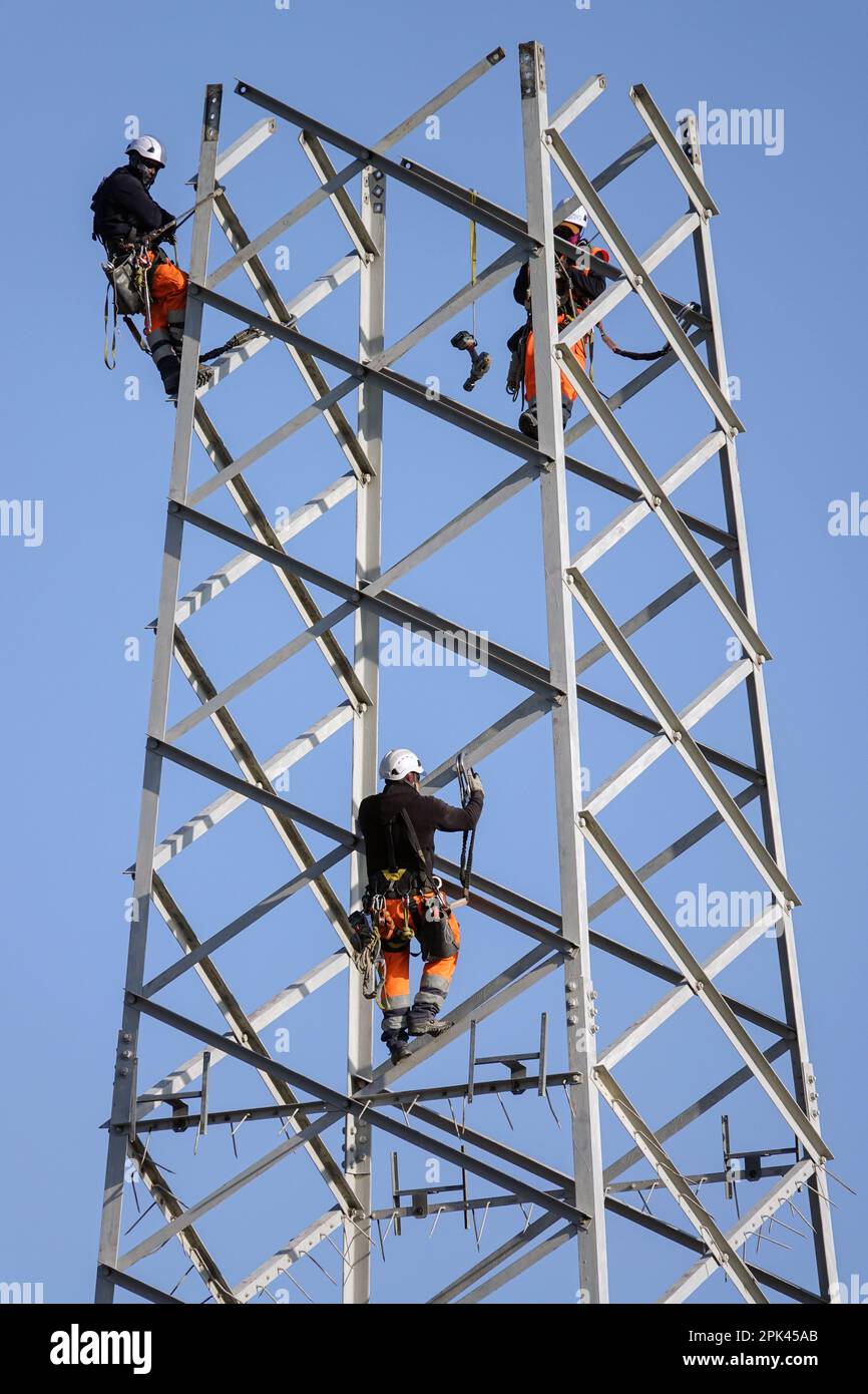 Gli elettricisti lavorano sopra la testa per smontare un traliccio ad alta tensione per la sostituzione. Milano, Italia - Aprile 2023 Foto Stock