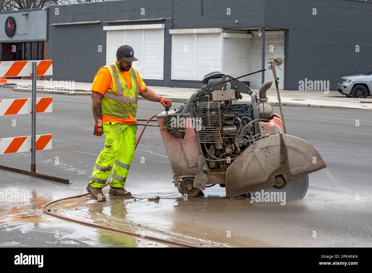 Detroit, Michigan - Un lavoratore gestisce una sega in cemento "walk-behind" come parte di un progetto per creare piste ciclabili protette, marciapiedi più ampi e per piantare tr Foto Stock
