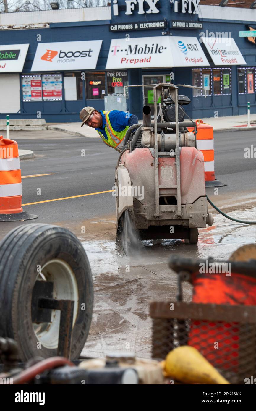 Detroit, Michigan - Un lavoratore gestisce una sega in cemento "walk-behind" come parte di un progetto per creare piste ciclabili protette, marciapiedi più ampi e per piantare tr Foto Stock