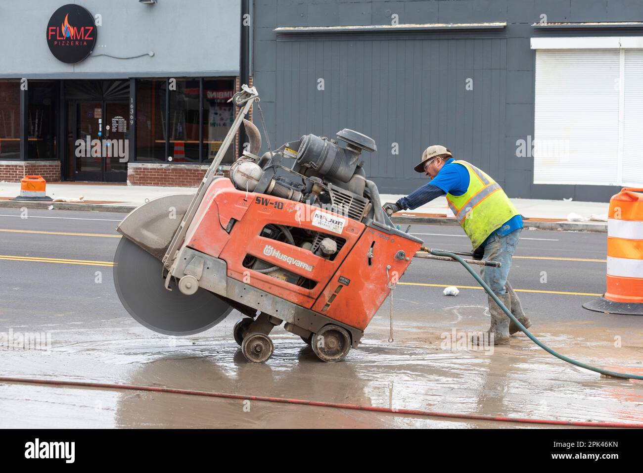 Detroit, Michigan - Un lavoratore gestisce una sega in cemento "walk-behind" come parte di un progetto per creare piste ciclabili protette, marciapiedi più ampi e per piantare tr Foto Stock