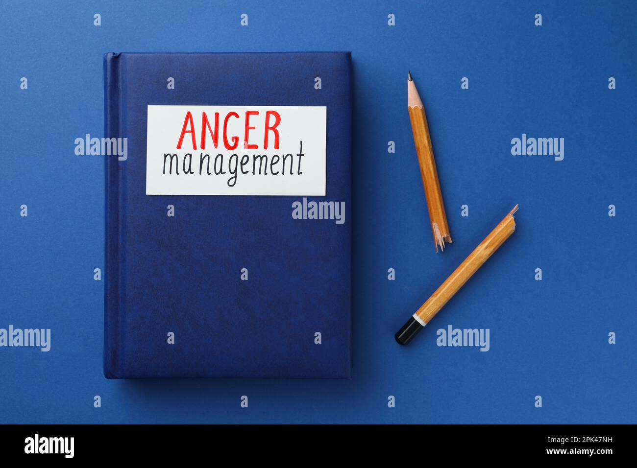 Notebook con parole Anger Gestione e matita spezzata su sfondo blu, piatto Foto Stock