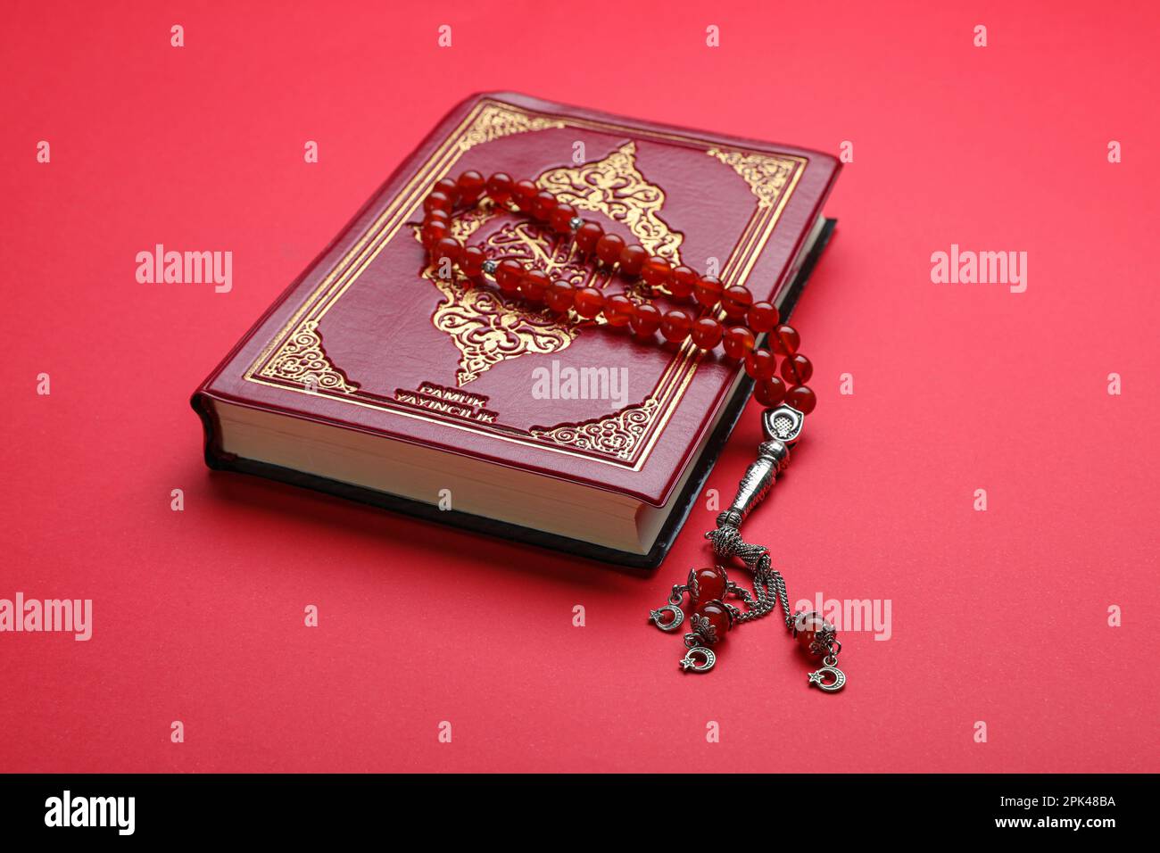 Perline di preghiera musulmane e Corano su sfondo rosso Foto Stock