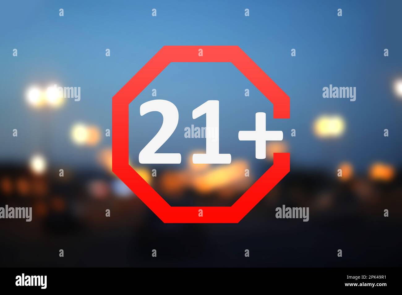 Segno limite di età 21+ anni e vista sfocata della città notturna Foto Stock