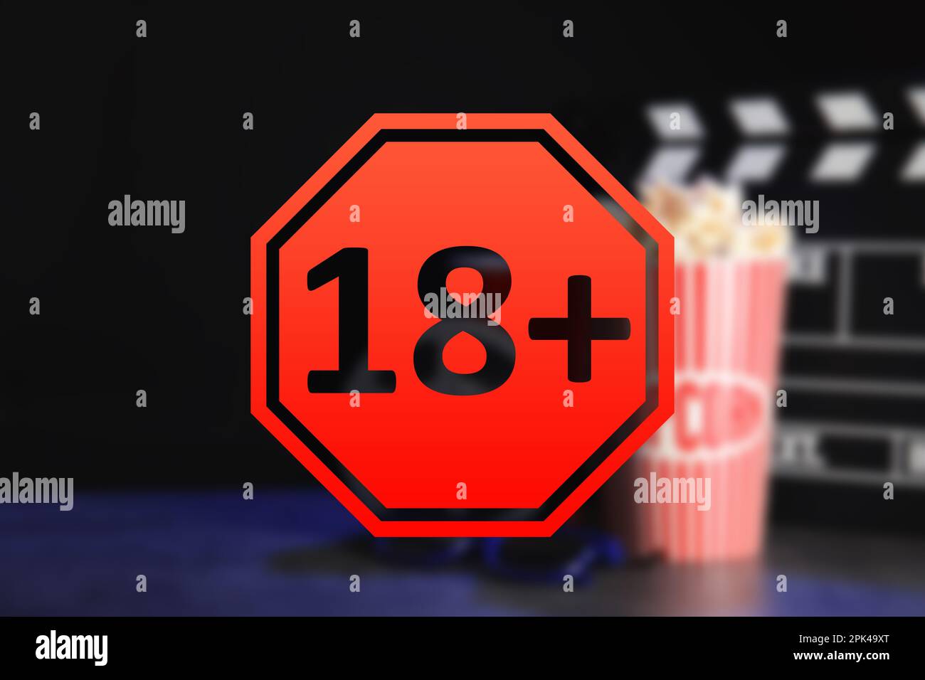 Segno limite di età 18+ anni e vista offuscata del clapperboard con popcorn Foto Stock