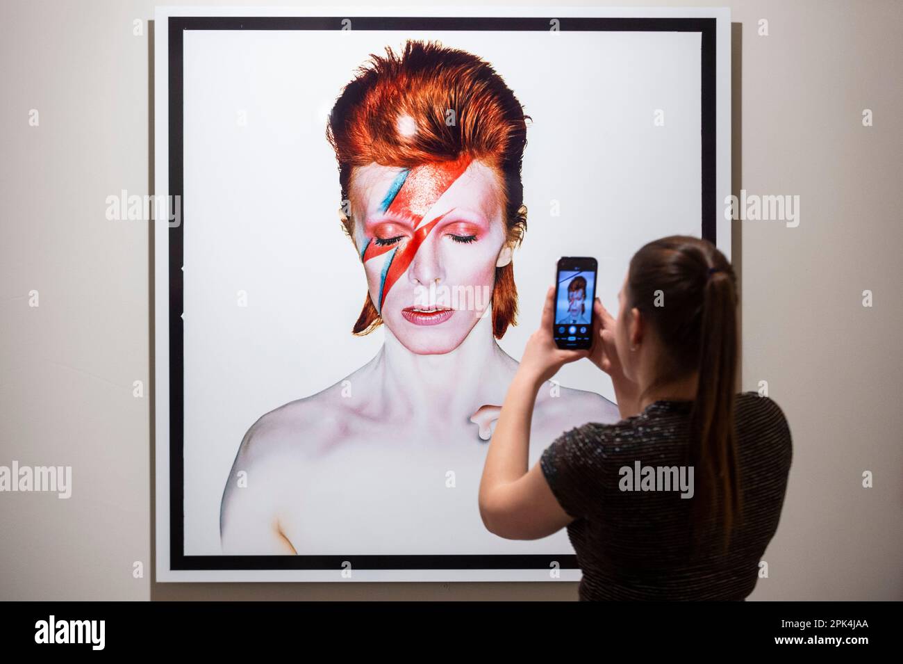 Londra, Regno Unito. 5 aprile 2023. Un membro dello staff scatta una foto di 'Aladdin sane, Eyes Shut', 1973, di Brian Duffy, in anteprima di 'Aladdin sane: 50 years', una nuova mostra al Royal Festival Hall del Southbank Centre. Cinquant’anni dopo l’uscita dell’album ‘Aladdin sane’ di David Bowie, la mostra esplora l’iconico ritratto di copertina ‘Lightning Bolt’ di Brian Duffy e la continua ridefinizione dell’immagine di Bowie. Lo spettacolo si svolge dal 6 aprile al 28 maggio. Credit: Stephen Chung / Alamy Live News Foto Stock