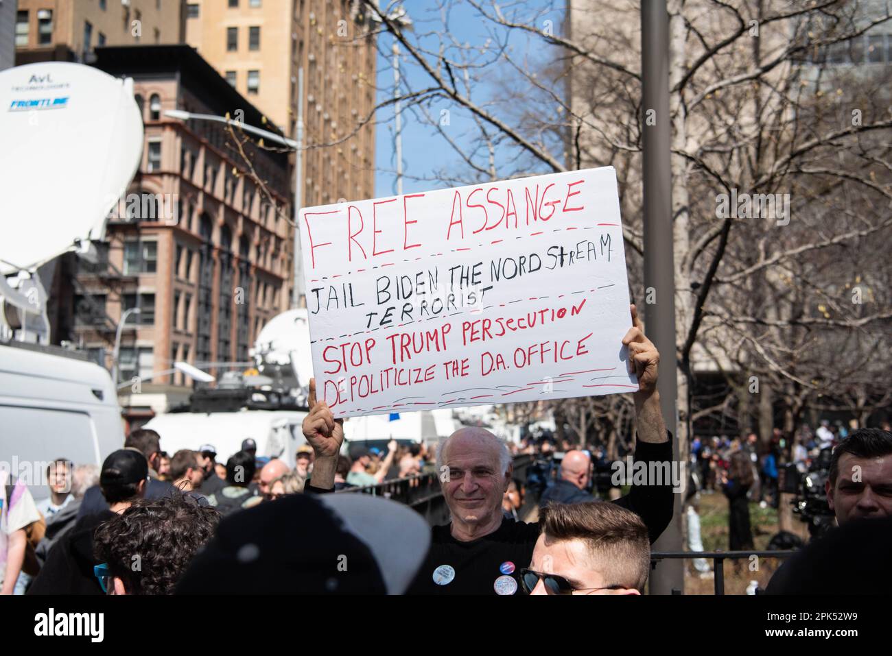 Un uomo con un cartello che dice "Free Assange Jail Biden the Nord Stream terrorist" e "Stop Trump persecution depoliticizzare il D.A. Ufficio' al di fuori dell'arraignment dell'ex presidente a Manhattan. Foto Stock