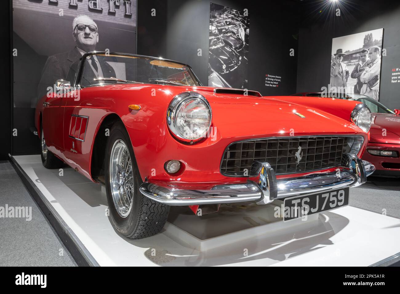 Sparkford.Somerset.United Kingdom.March 26th 2023.A 1960 Ferrari 250 GT cabriolet è in mostra davanti ad un ritratto di Enzo Ferrari al Haynes Moto Foto Stock