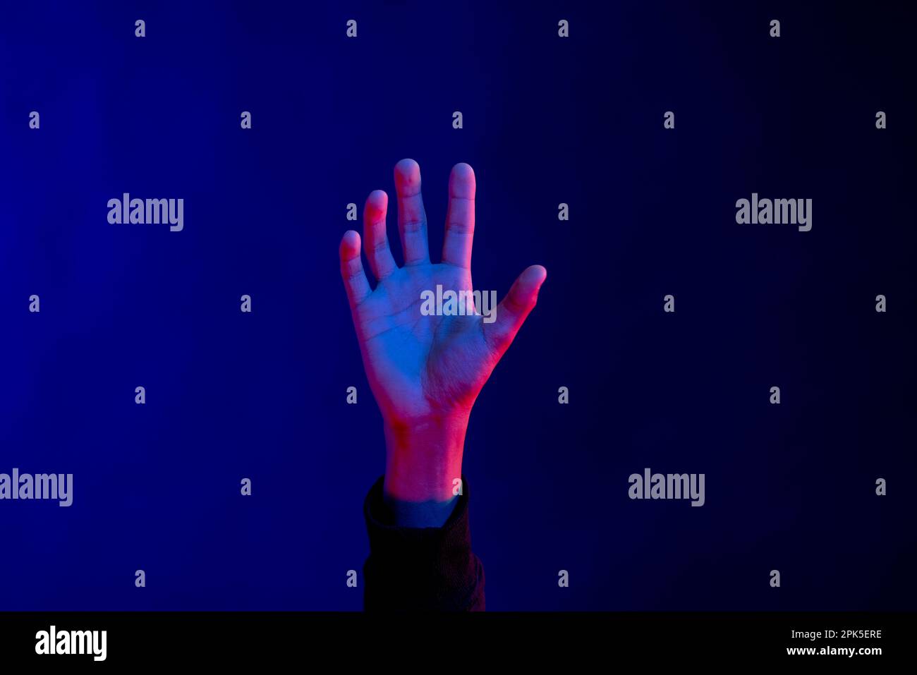 Uomo asiatico a mano aperta in studio con luce blu con spazio copia Foto Stock