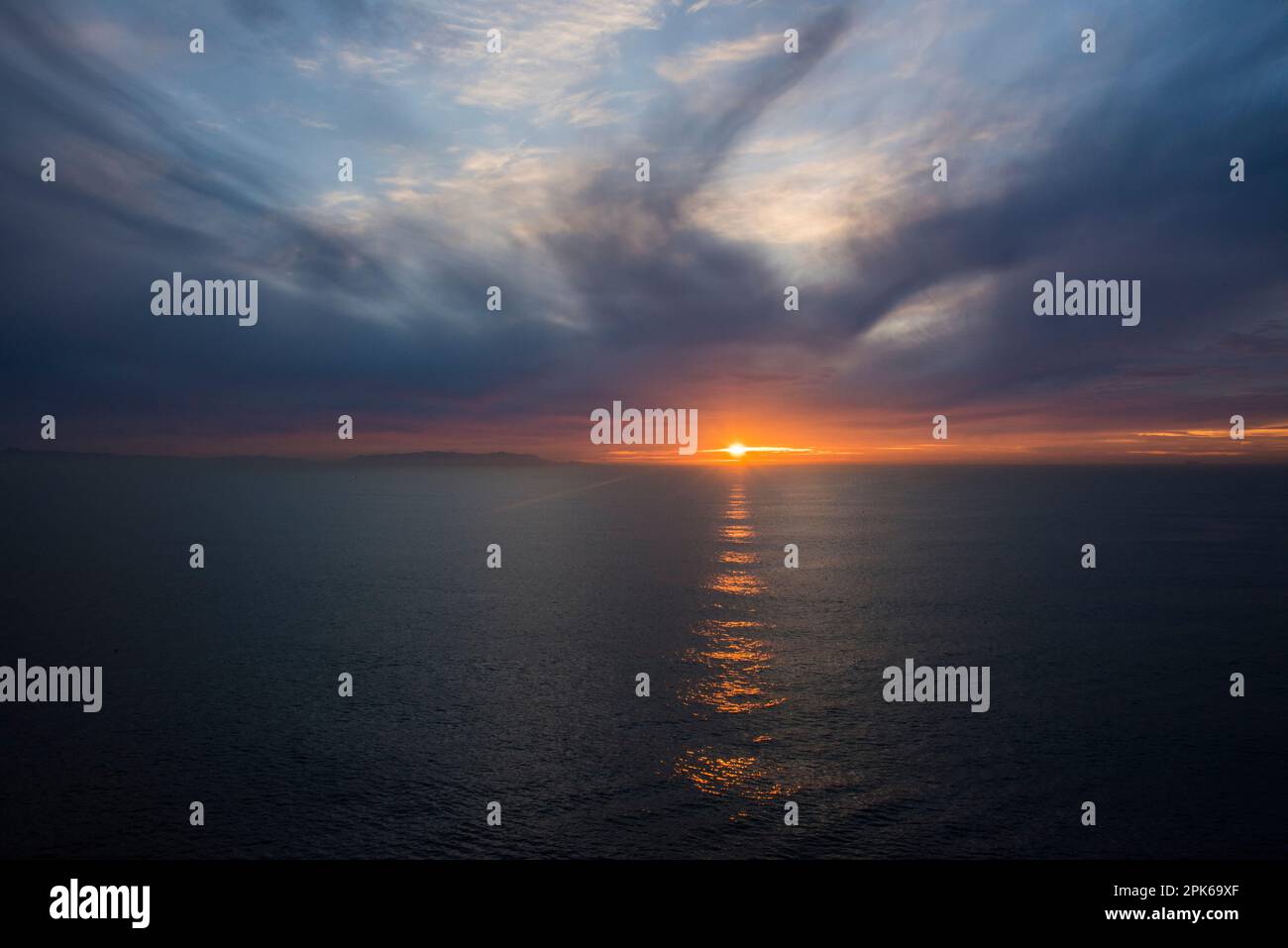 Un tramonto lontano al largo della costa della California vicino a Los Angeles, Stati Uniti. Concetto di distanza, speranza, luce tra le nuvole e l'oceano. Foto Stock