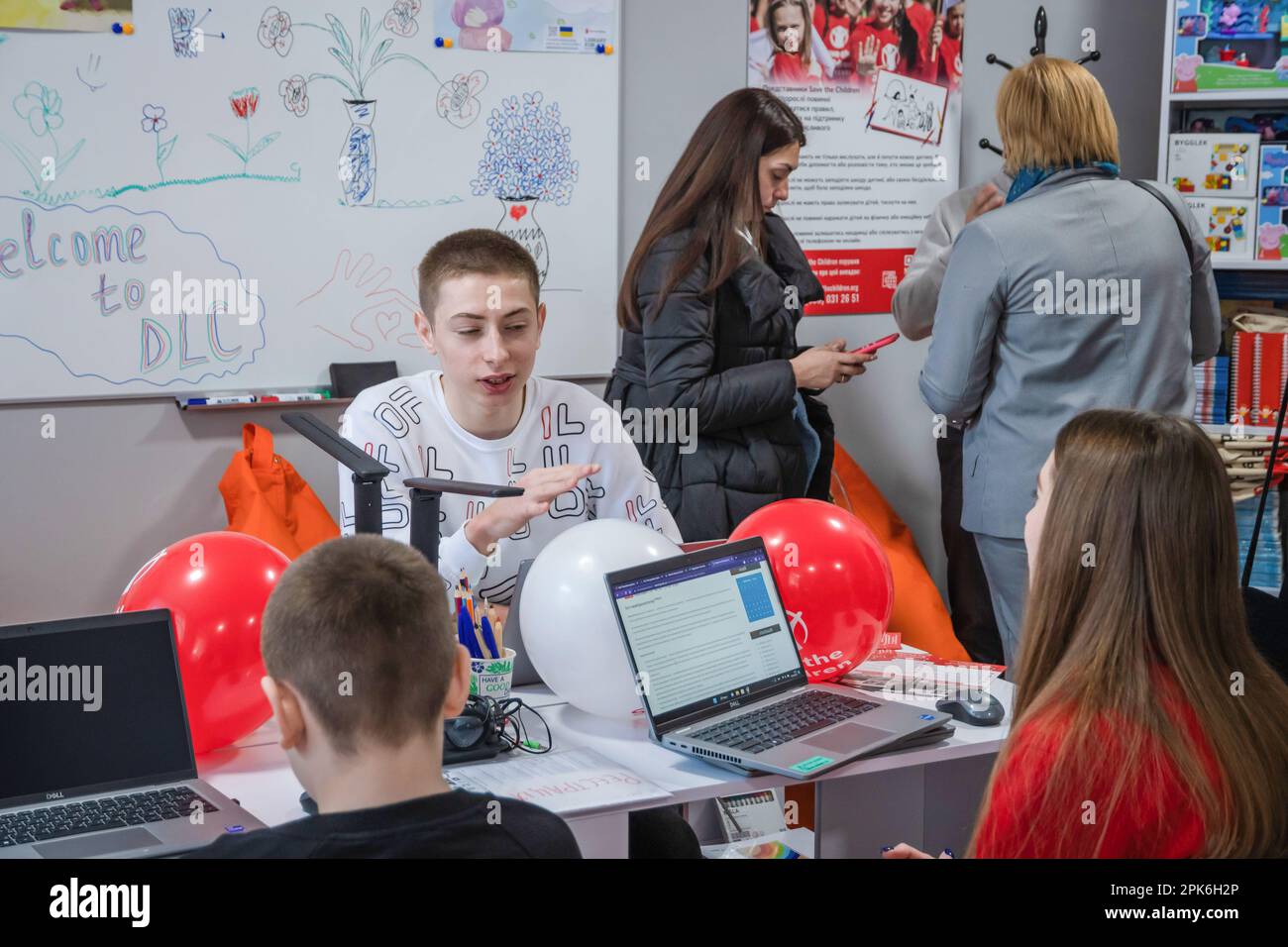 I bambini siedono a un tavolo con computer portatili e tablet in classe. Apertura ufficiale del Centro di apprendimento digitale nella Scuola superiore professionale di tecnologie informatiche e costruzione di Lviv, fondata dall'organizzazione umanitaria internazionale Save the Children con il sostegno del Ministero degli Affari Esteri norvegese. L'obiettivo del Digital Learning Center è un accesso sicuro all'apprendimento a distanza per i bambini dai 6 ai 17 anni, accesso all'istruzione interattiva non formale. Il centro di apprendimento digitale garantisce ai bambini un accesso continuo all'istruzione e alla socializzazione interna di Foto Stock