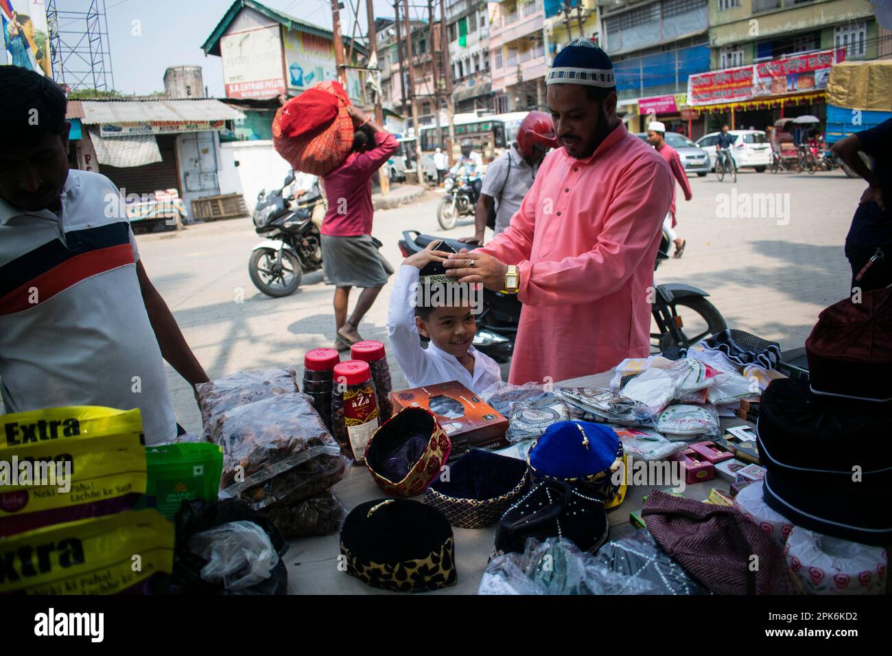 Il padre musulmano indiano compra il cappello per il suo figlio prima di eseguire la preghiera del secondo venerdì nel mese santo di Ramadan ad una moschea in Guwahati, India sopra Foto Stock
