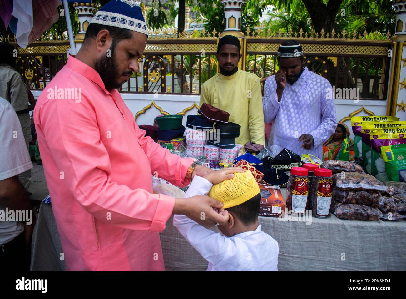 Il padre musulmano indiano compra il cappello per il suo figlio prima di eseguire la preghiera del secondo venerdì nel mese santo di Ramadan ad una moschea in Guwahati, India sopra Foto Stock