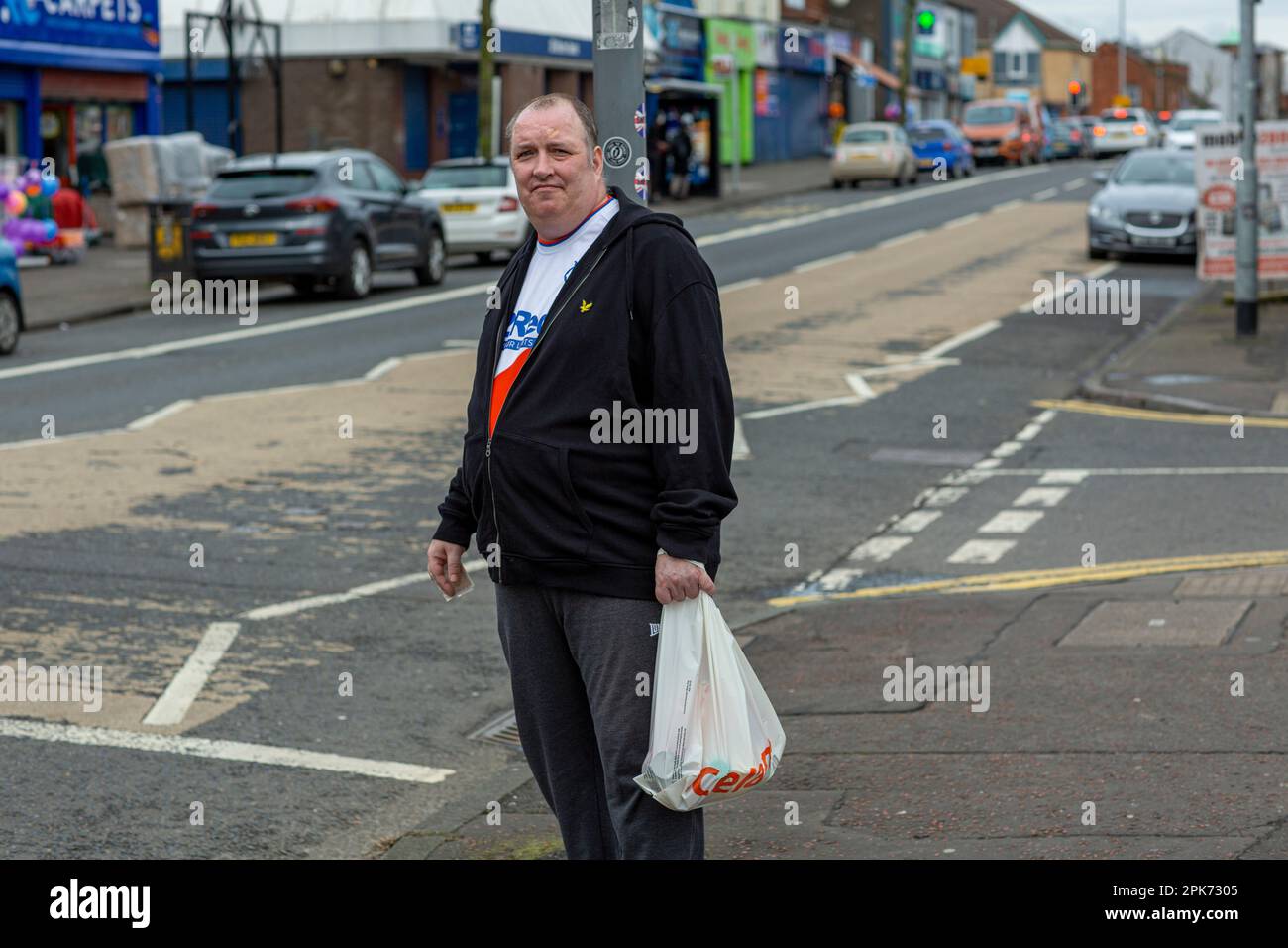 Uomo che porta lo shopping su Shankill Road a Belfast, County Antrim, Irlanda del Nord, Regno Unito Foto Stock