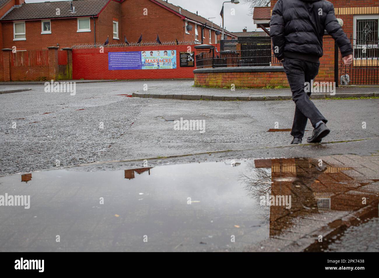 Pedoni che camminano davanti ad un murale che commemora il massacro di Springhill, Beechmount Avenue, belfast, contea di antrim, Irlanda del Nord, regno unito. Foto Stock