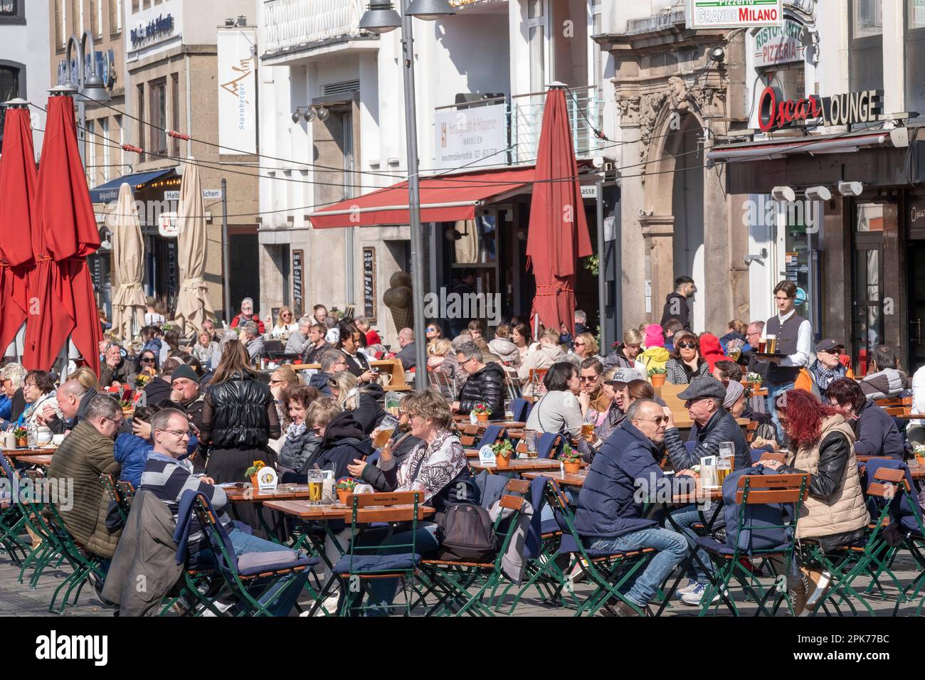 Le persone che si godono una giornata di sole primaverili sulla piazza Heumarkt di Colonia Foto Stock