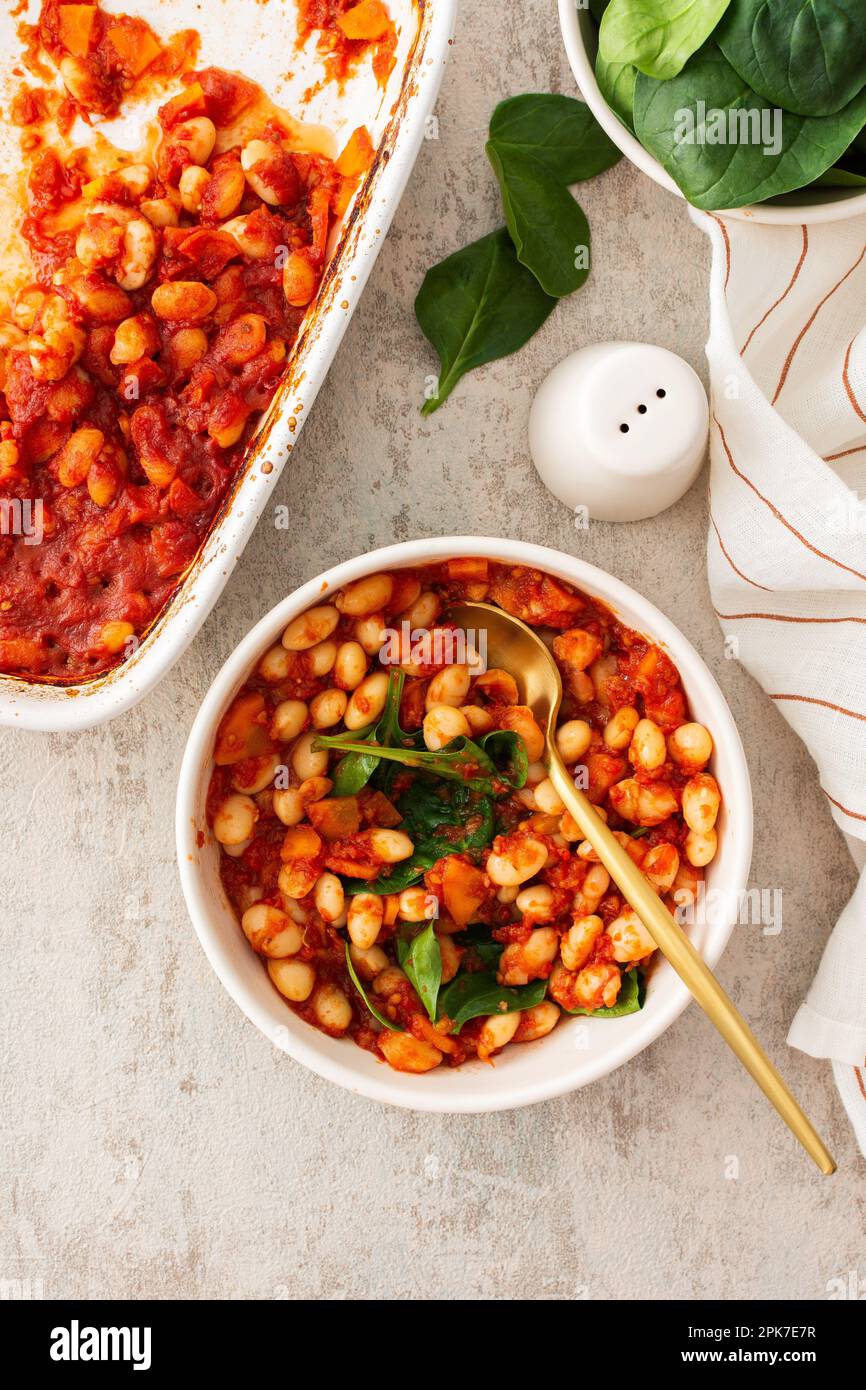 Colazioni e pranzi sani, fagioli bianchi stufati con carote, cipolle e pomodori con foglie di spinaci, una ciotola di fagioli e spinaci Foto Stock