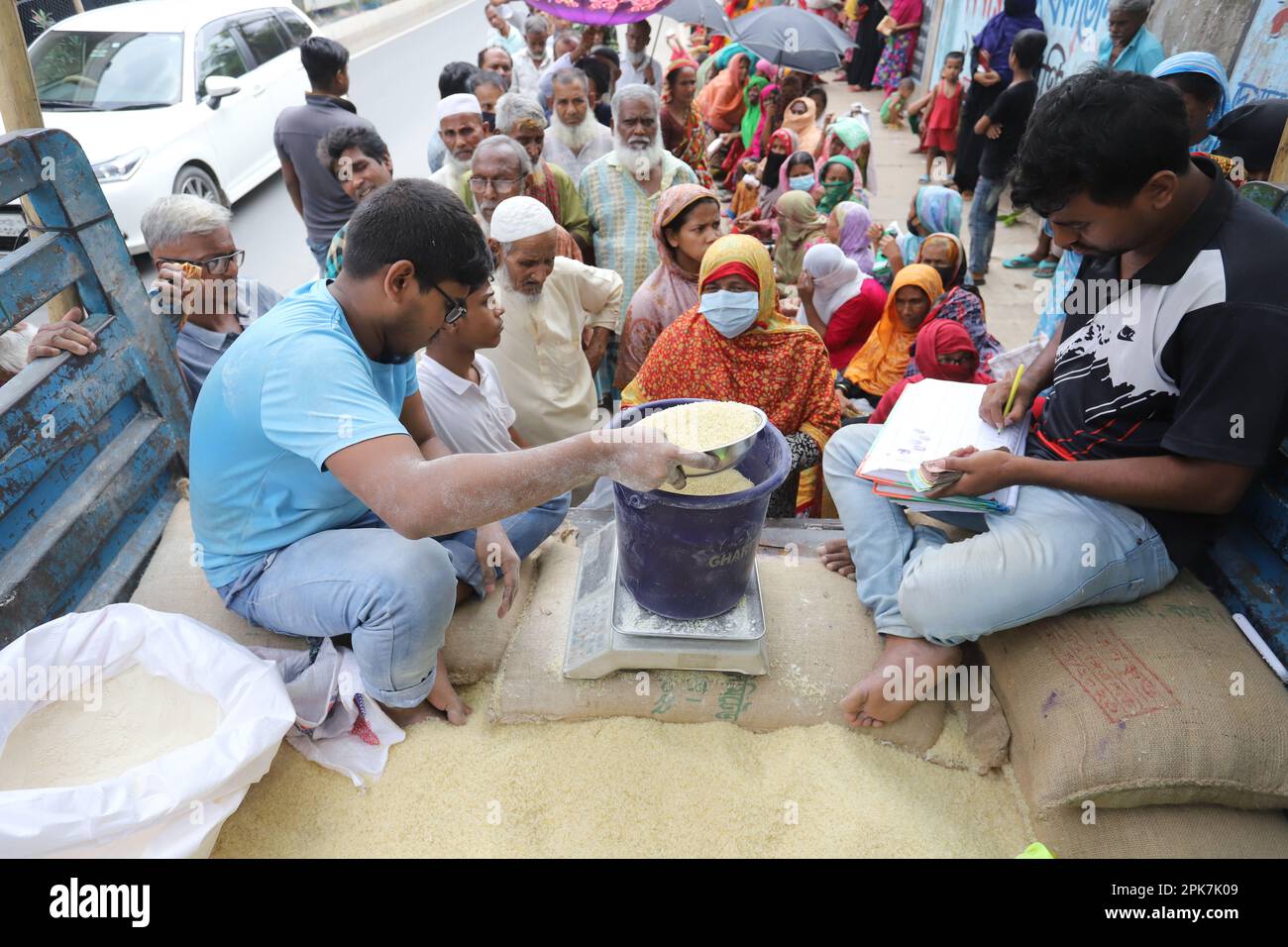 Persone provenienti da gruppi a basso reddito aspettano in coda davanti ai camion OMS del reparto alimentare per ore per comprare riso e atta (farina integrale), sperando di t Foto Stock