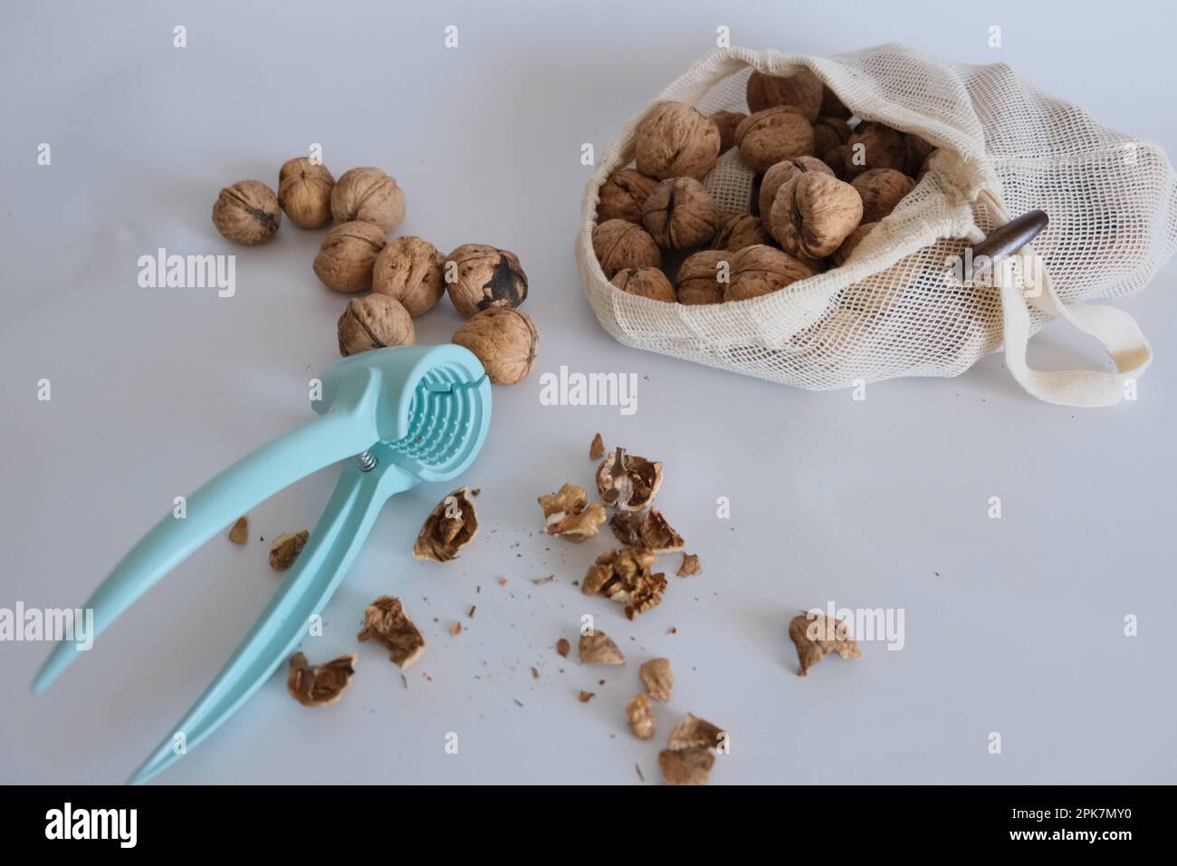 Cracker con noce sgusciata su fondo bianco con una borsa di stoffa bianca piena di noce sgusciata. Idea di concetto di cracker di noce. Foto Stock