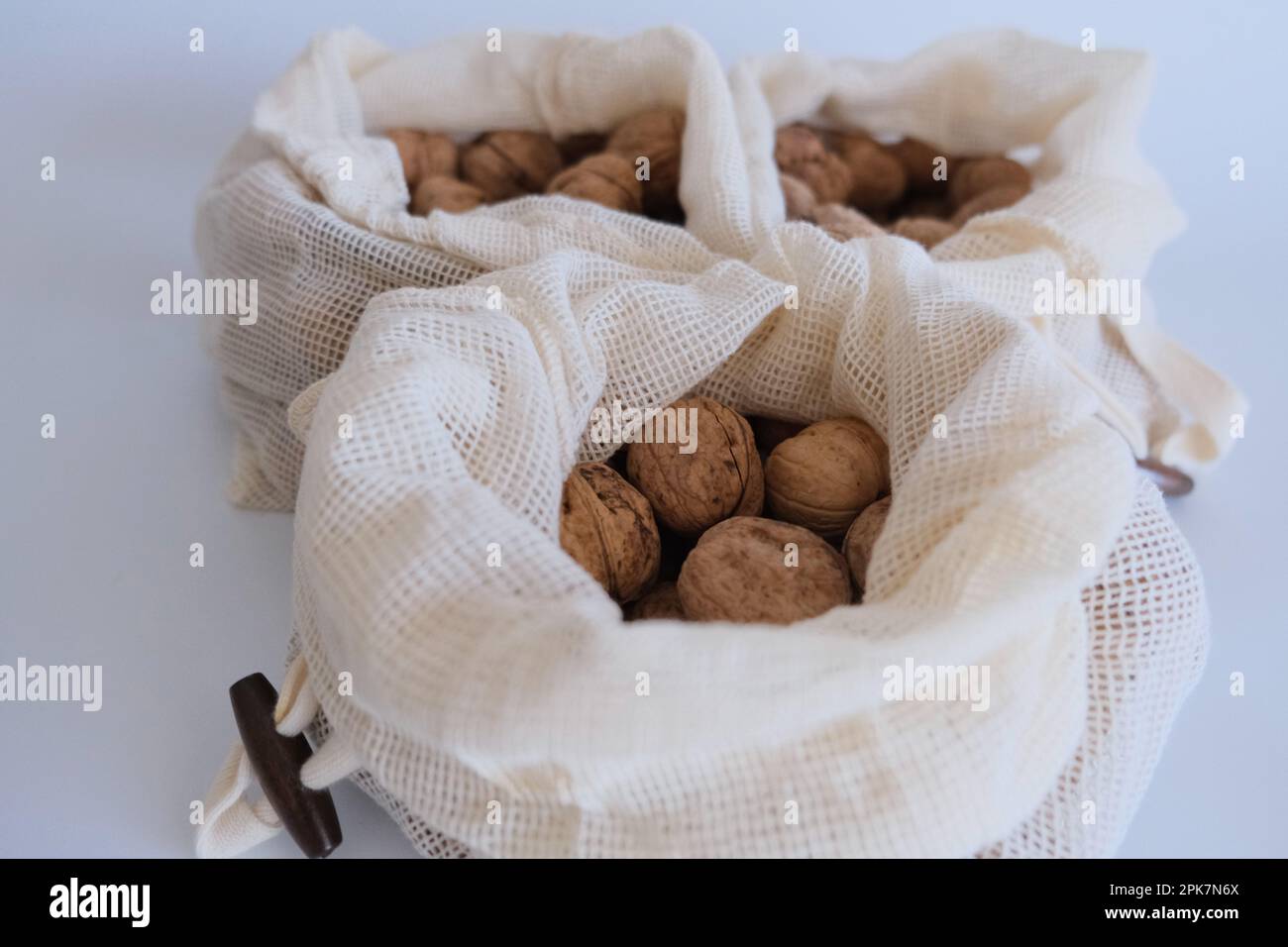 Noci sgusciate, mucchio di noci sgusciate in tre sacchetti di stoffa bianca su fondo bianco. Sacchetti di stoffa pieni di idea di concetto di noci sgusciate. Foto Stock