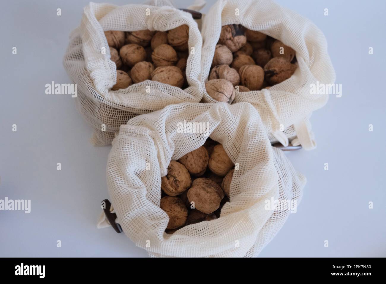 Noci sgusciate, mucchio di noci sgusciate in tre sacchetti di stoffa bianca su fondo bianco. Sacchetti di stoffa pieni di idea di concetto di noci sgusciate. Foto Stock