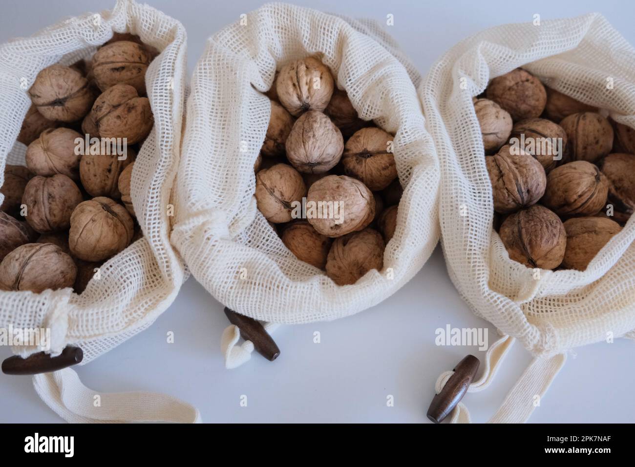 Noci sgusciate, mucchio di noci sgusciate in tre sacchetti di stoffa bianca su fondo bianco affiancati. Sacchetti di stoffa pieni di concetto di noci sgusciate. Foto Stock