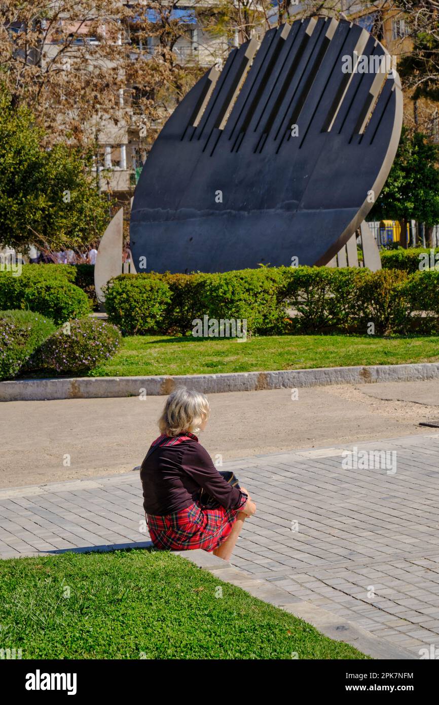 Donna siede di fronte alla scultura Promahones nei giardini del Museo Archeologico Nazionale, Atene in primavera Foto Stock