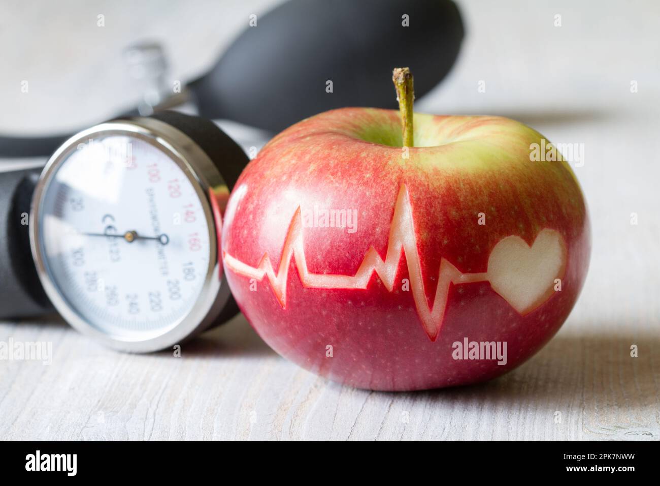 Linea heartbeat sulla mela rossa e sfigmomanometro, concetto di dieta sana del cuore Foto Stock