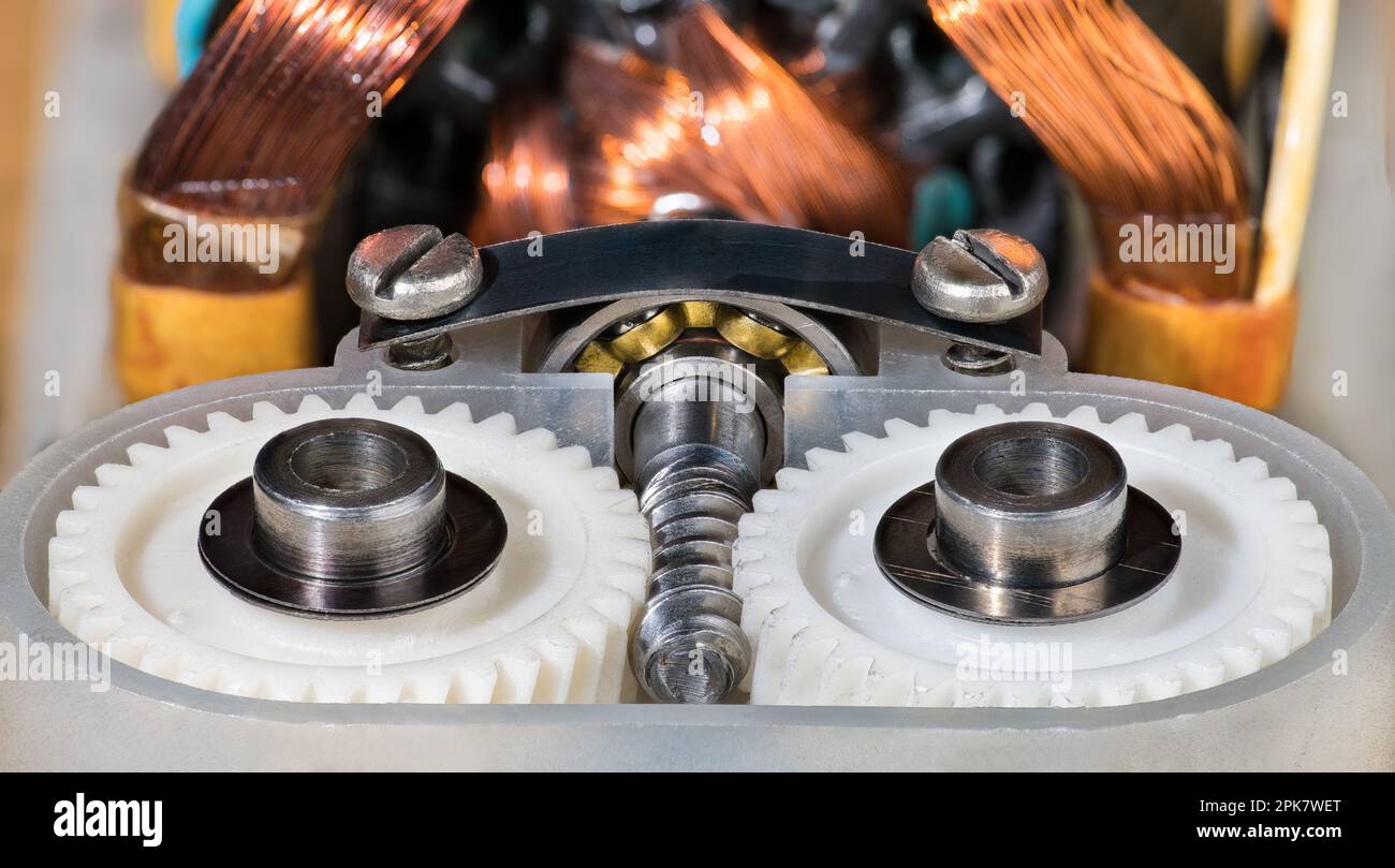 Primo piano delle ruote dentate in plastica della trasmissione del motore elettrico, della vite senza fine in metallo e del cuscinetto a sfere. Avvolgimento del filo di rame del rotore e dello statore all'interno del vecchio miscelatore. Foto Stock