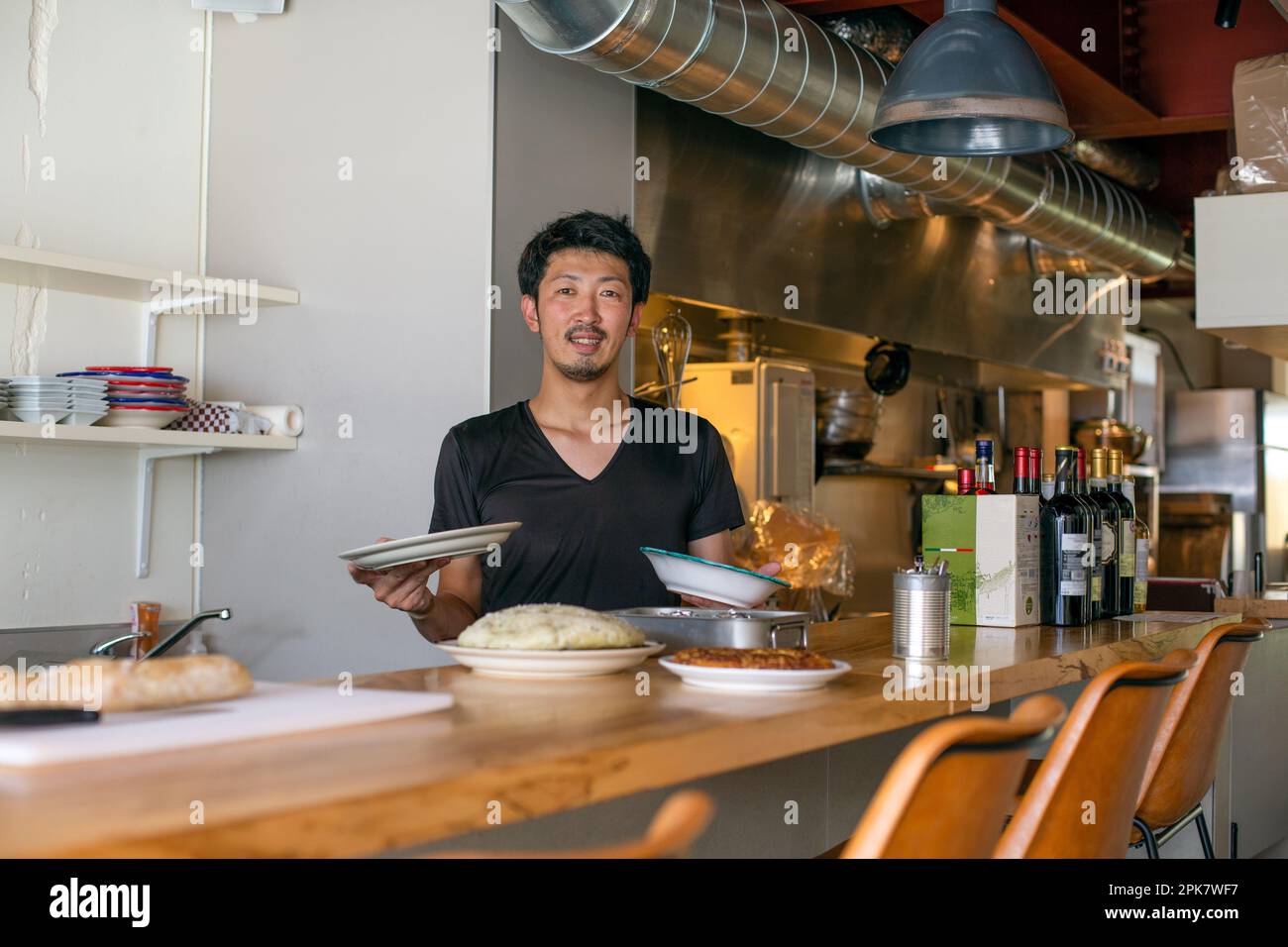Uno chef che lavora in un ristorante, al passo preparare piatti di cibo per il servizio, Foto Stock
