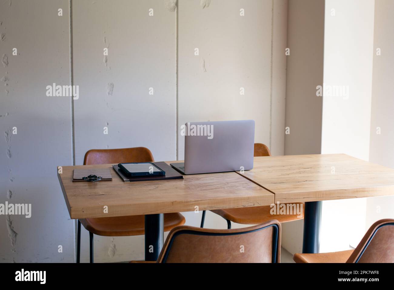 Un ristorante con pareti bianche e tavoli e sedie in legno. Foto Stock