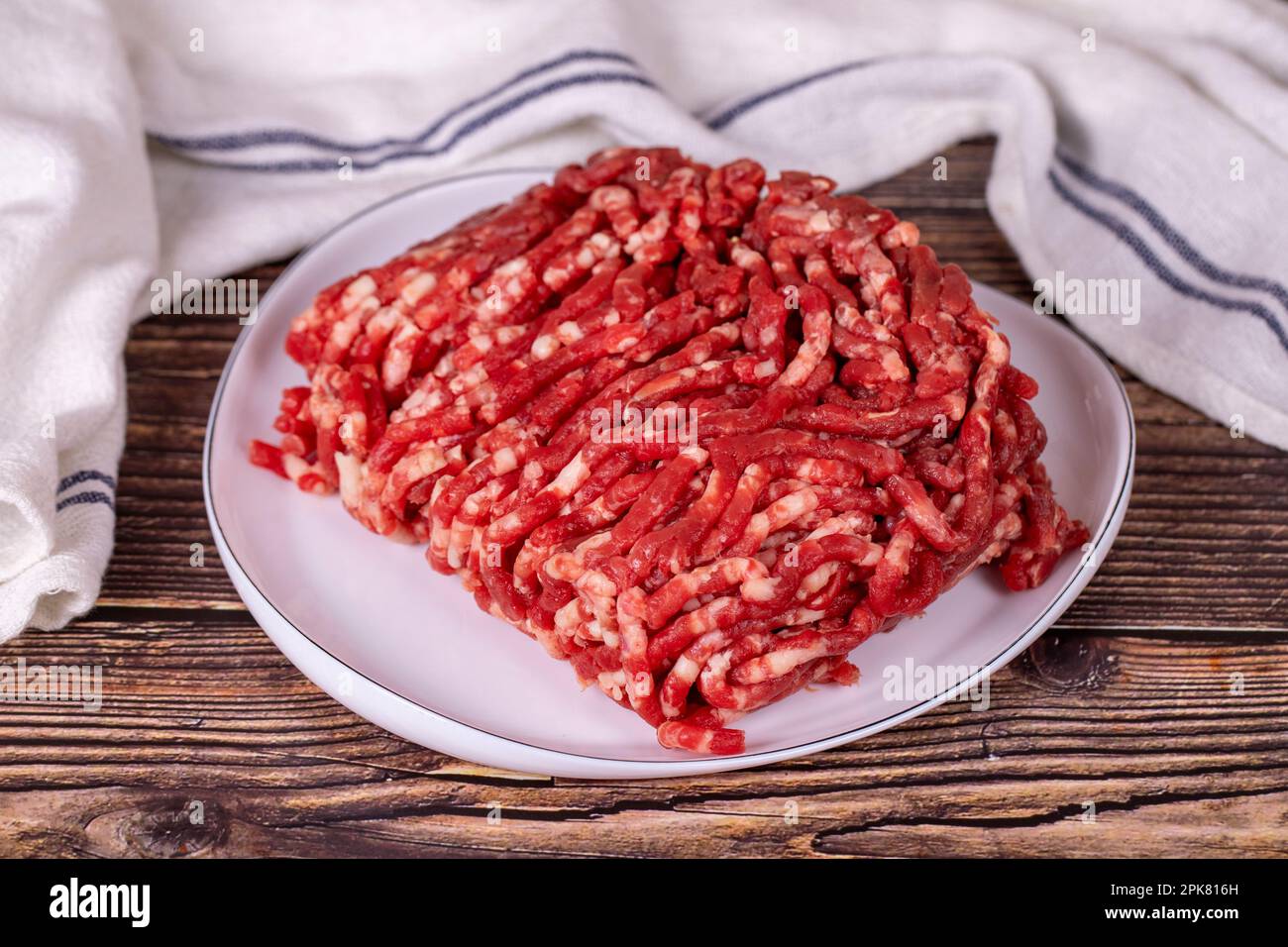 Carne macinata sul piatto. Macinato di manzo fresco su sfondo di legno. Foto Stock