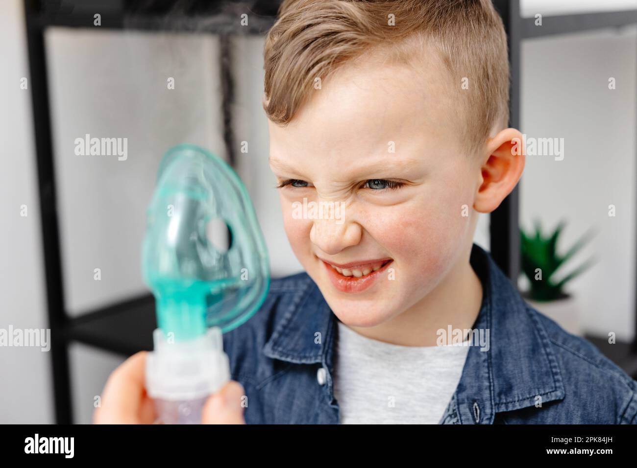 Il ragazzo carino mostra emozione dispiaciute prima di inalare. Foto Stock