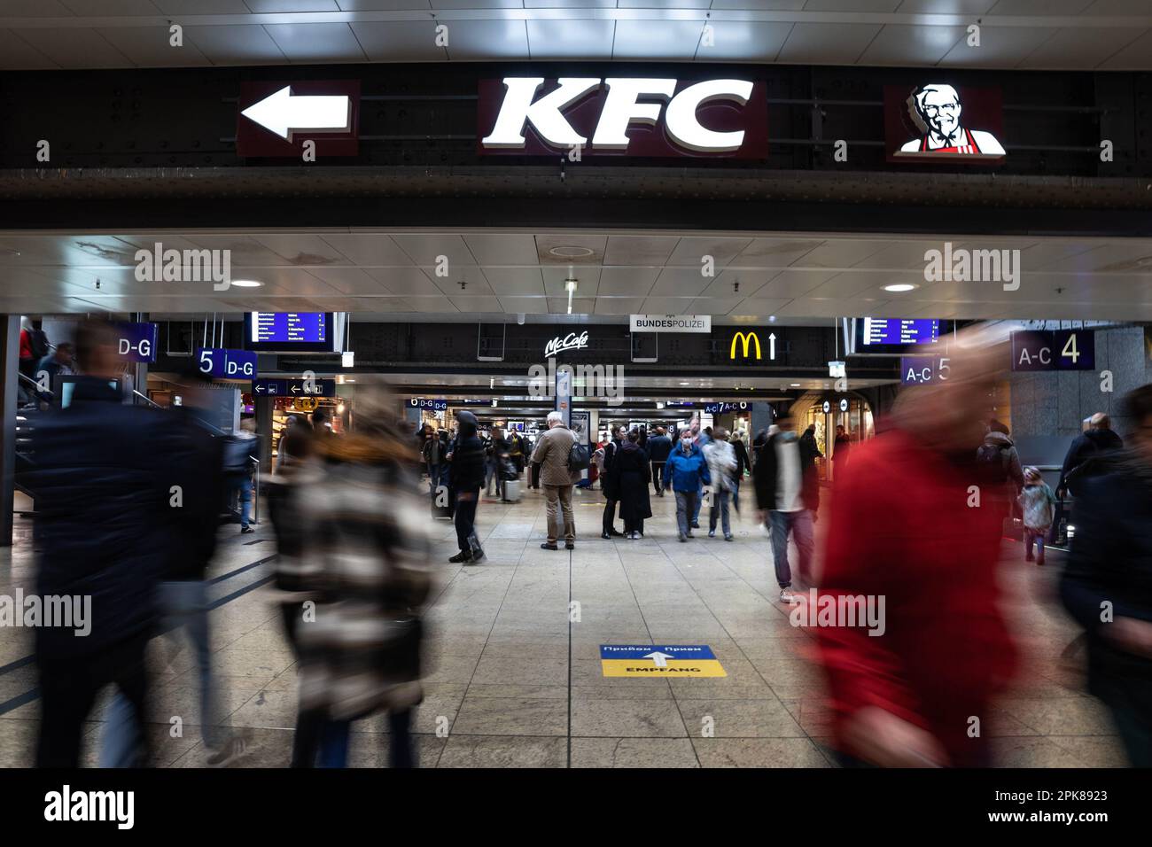 Foto dell'atrio sotterraneo di Koln Hbf con persone che corrono a Colonia, in Germania, passando per un logo del locale KFC fast food. Il KFC è un americano Foto Stock