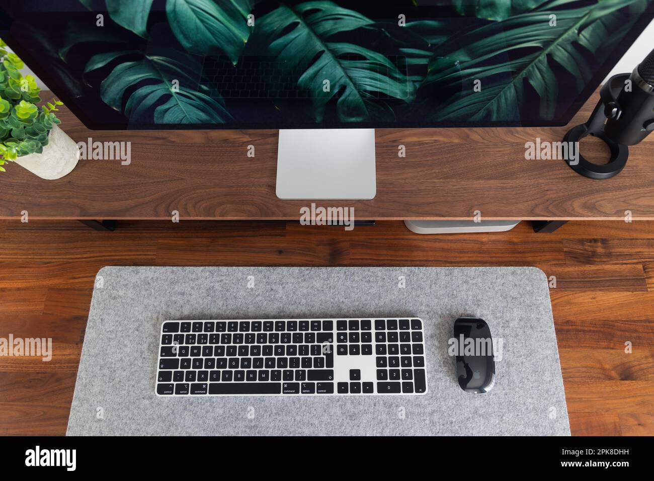 LONDRA - 06 APRILE 2023: Configurazione minima della scrivania in un moderno ufficio domestico con tastiera Apple computer scrivania e piante in legno di noce Foto Stock