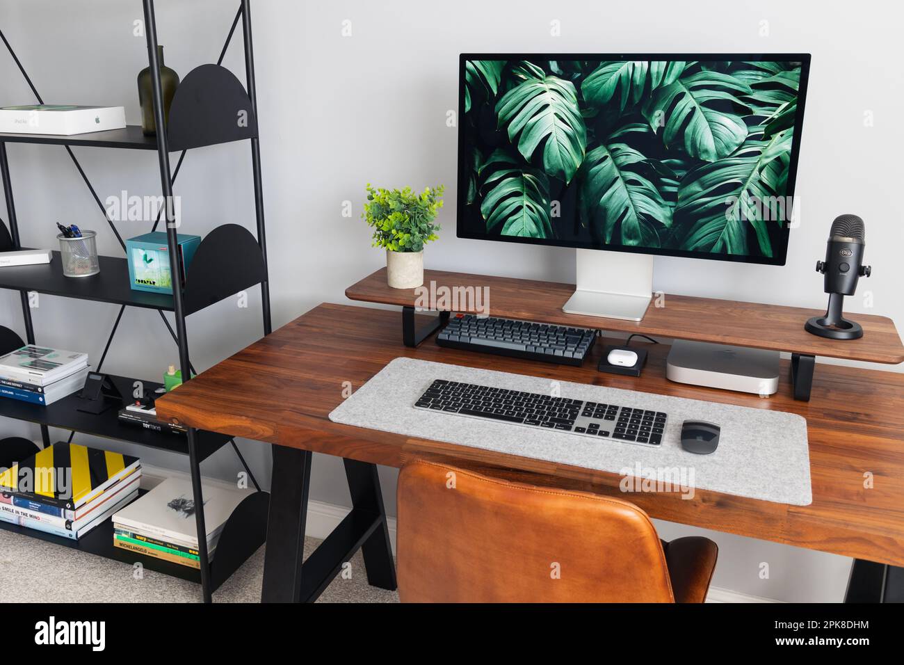 LONDRA - 06 APRILE 2023: Configurazione minima della scrivania in un moderno ufficio domestico con tastiera Apple computer scrivania e piante in legno di noce Foto Stock