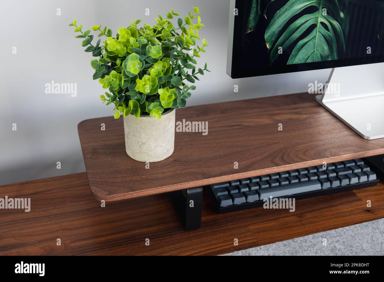 LONDRA - 06 APRILE 2023: Configurazione minima della scrivania in un moderno ufficio domestico con tastiera Apple computer scrivania e piante in legno di noce Foto Stock