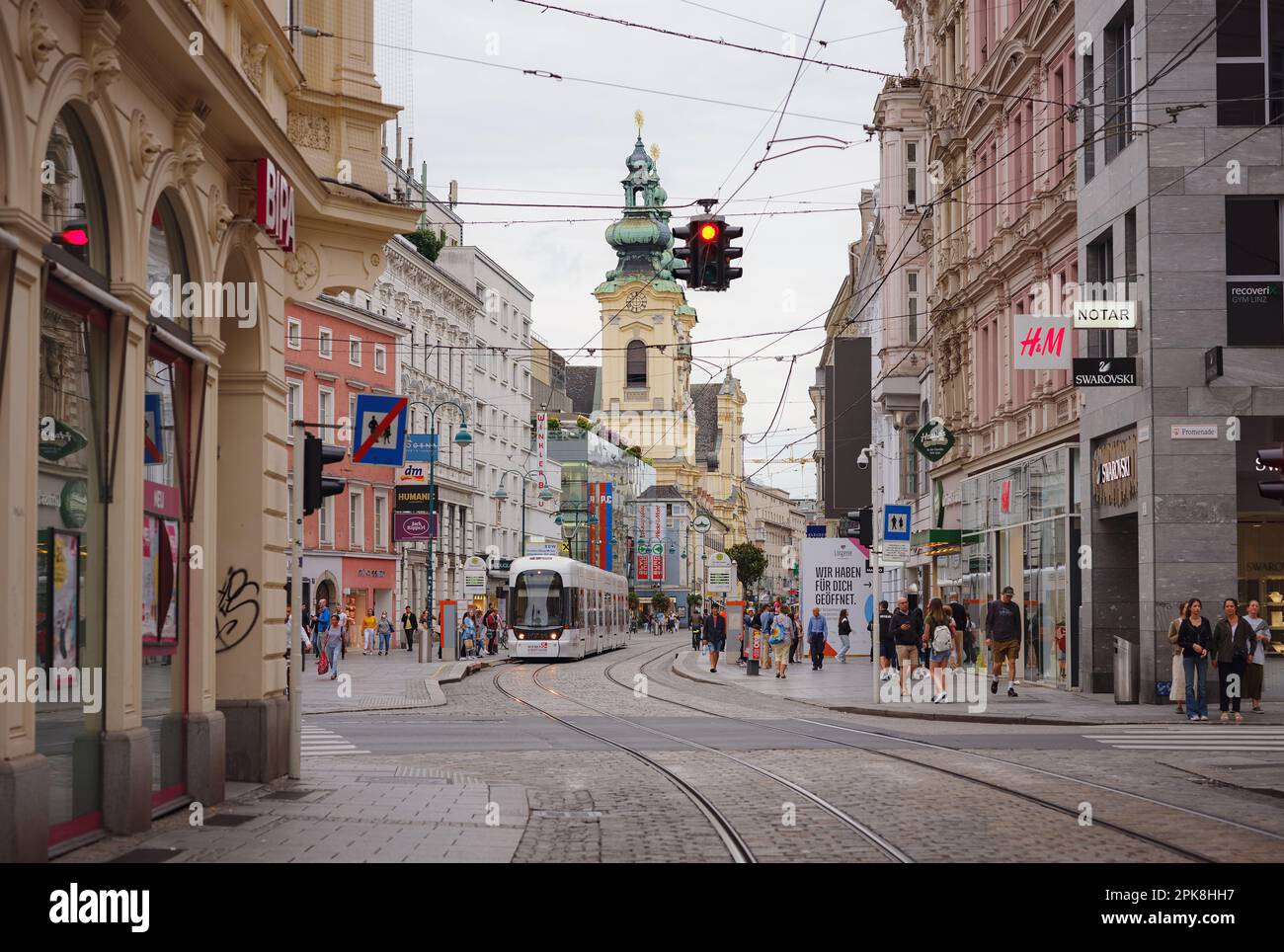 Linz, Austria - 6 agosto 2022 : Visualizza attraverso la strada principale della città con persone a piedi, negozi e linee del tram. Linz è la terza città più grande Foto Stock